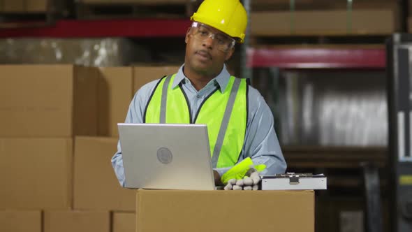 Worker looks at laptop computer in shipping warehouse