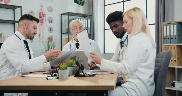 Different Ages Diverse Group of Doctors Discussing Working Moments During Meeting in Medical office