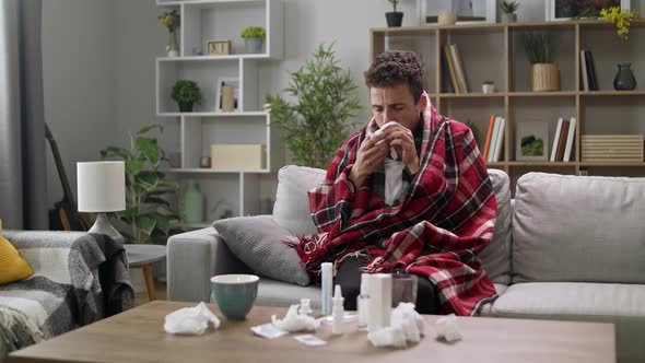 The Sick Man Blows His Nose in a Napkin in the Living Room