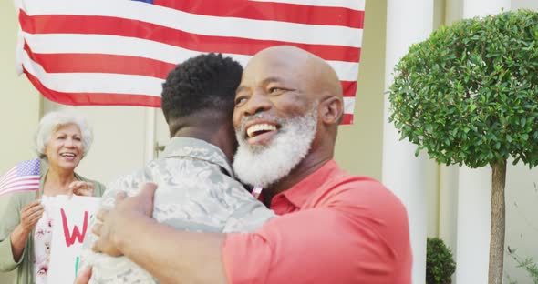 African american male soldier embracing his smiling father over family and american flag