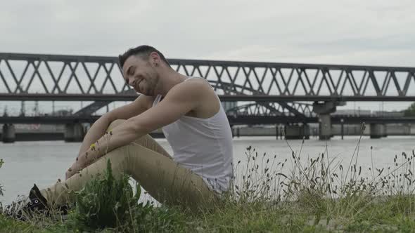 Side view of positive young male in casual outfit rotating head and looking at camera with smile whi