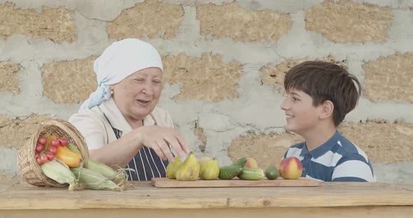 A Teenager and His Grandmother are Resting Against the Background of the Harvested Crop From the