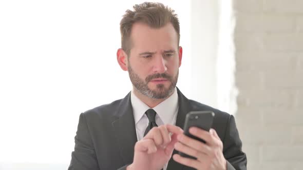 Young Businessman Reacting to Loss on Smartphone