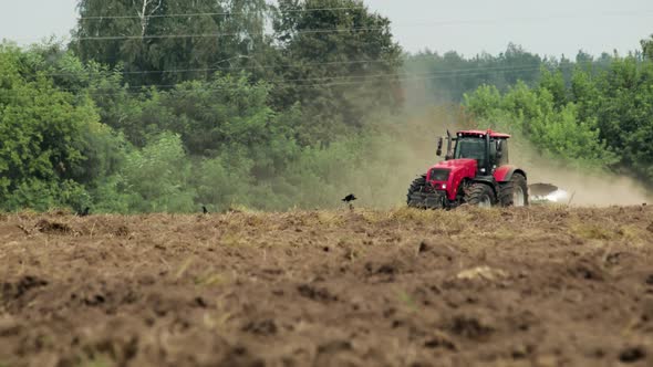 Tractor with Plow Cultivates Dusty Field