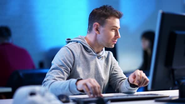 Handsome Caucasian Man Talking To Blurred Woman at Background and Typing on Computer Keyboard