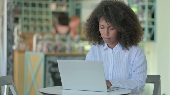 African Businesswoman with Laptop Looking at Camera in Cafe