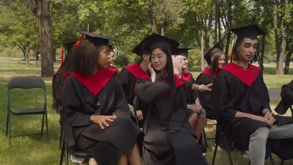 Happy Multiracial Classmates Greeting Each Other at Graduation Ceremony