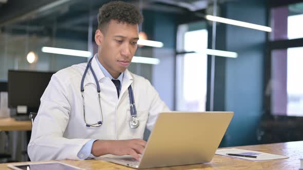 Focused Young Doctor Working on Laptop in Modern Office 