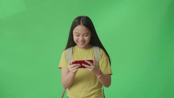 Asian Girl Student Playing Game On Mobile Phone And Walking To School On Green Screen Chroma Key