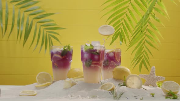 Pieces of Lime Fall Into a Glass of Refreshing Summer Lemonade Cocktail