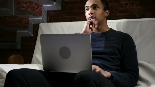 Pensive Thinking African Man Working on Laptop at Night