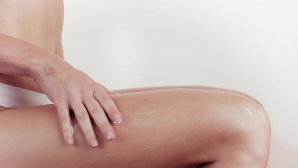 Woman Applying Moisturizer Cream or Body Lotion on Her Legs