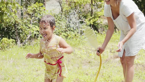 Little Girl Dancing Under the Spray From a Garden Hose