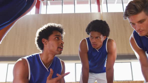 Diverse male basketball team in huddle discussing game tactics