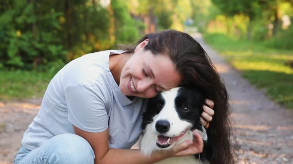 Smiling Young Attractive Woman Playing with Cute Puppy Dog Border Collie on Summer Outdoor