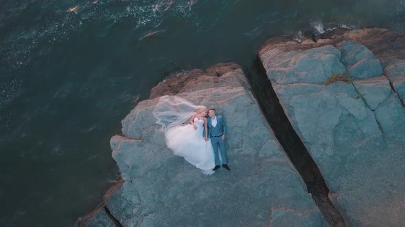 Wedding Newlyweds Couple Are Lying on a Mountainside By the Sea. Aerial Shot