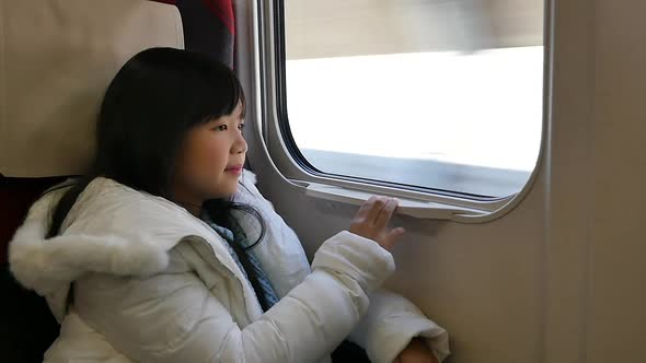 Little Asian Girl Looking Through Window. She Travels On A Train Slow Motion