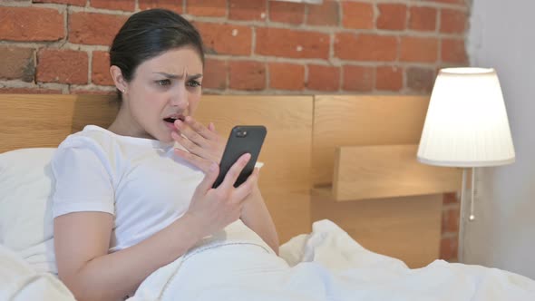 Young Indian Woman Reacting to Loss on Smartphone in Bed