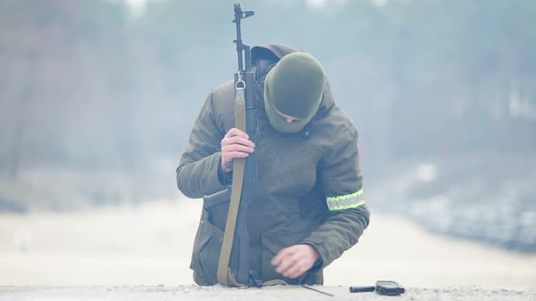 Portrait of Serious Focused Recruit Disassembling Military Weapon Outdoors