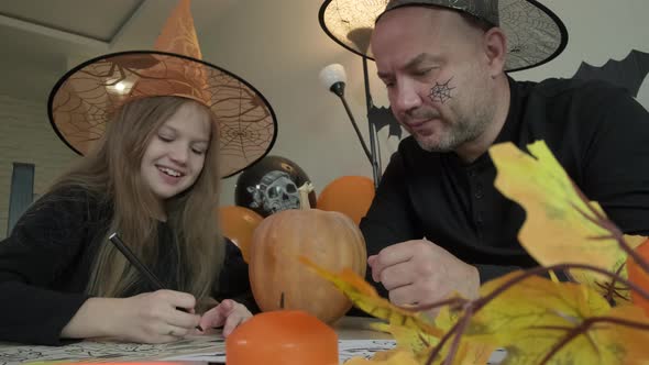 Child with Father Draw Pictures on the Theme of Halloween in Decorated Room at Home