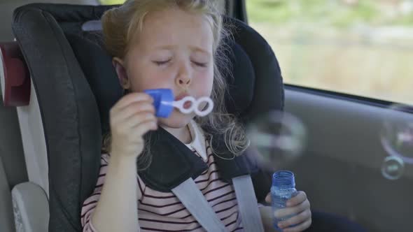 Lovely Little Girl Blowing Soap Bubbles in Car
