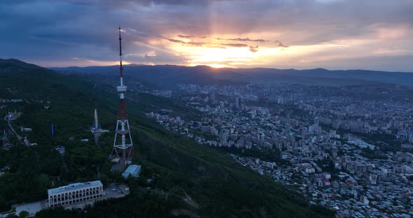 Aerial view of center of Tbilisi under Mtatsminda mountain at sunset. Georgia 2022 summer