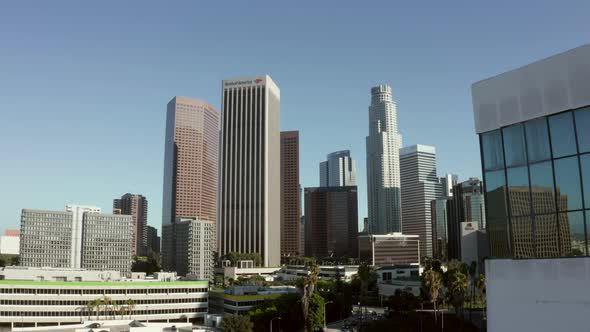 AERIAL Reveal of Downtown Los Angeles California Skyline Behind Building with Glass Windows at