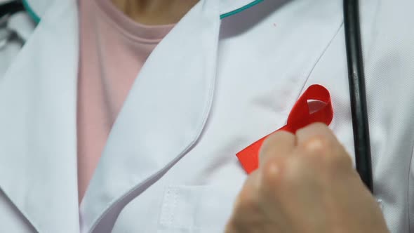 Doctor Pins Up Red Ribbon, Concept of AIDS Awareness, Prevention and Treatment