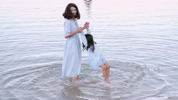 Pretty Mother Is Playing with Daughter in the Lake