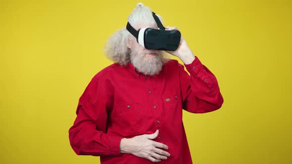 Portrait of Senior Greyhaired Man Wearing Virtual Reality Simulator Looking Around and Laughing Out