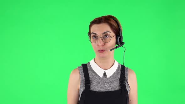 Portrait of Funny Girl in Round Glasses with Headset Helping with Customer Service. Green Screen