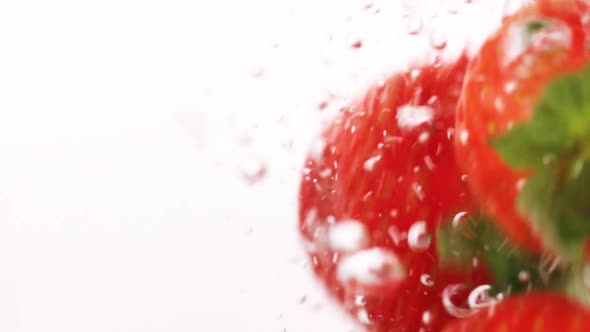 Strawberry Falling Into the Water with Bubbles on White Background