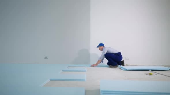 Professional Male Builder Performs Construction Work Insulates Floor with Polyurethane Foam Before