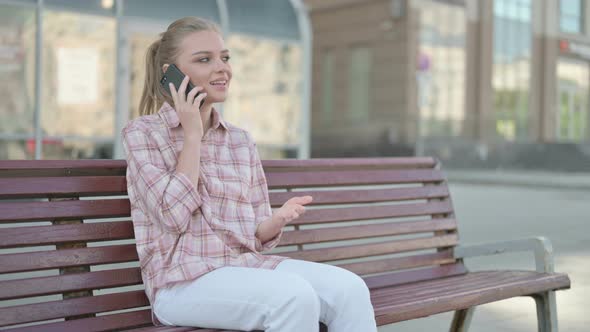 Young Woman Talking on Phone While Sitting Outdoor on Bench