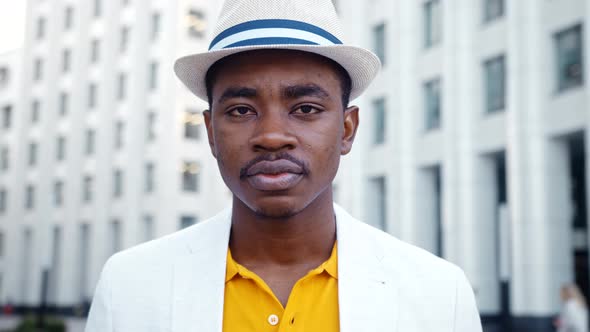 African American man in white classic suit looks straight with serious face