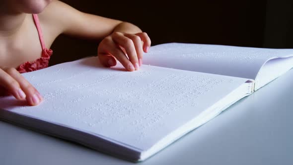 Schoolgirl reading a braille book in classroom
