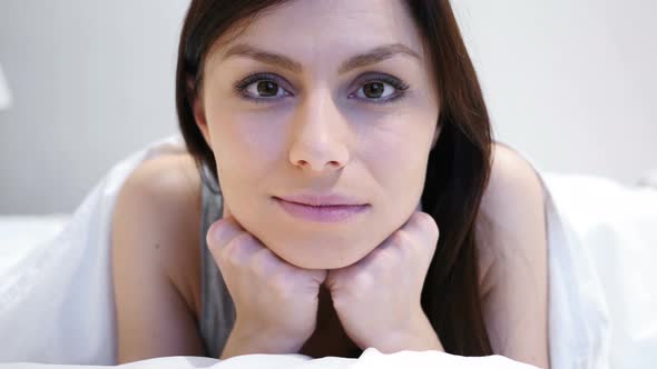 Woman Lying on Stomach in Bed Looking at Camera