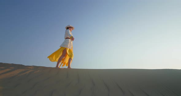 Cheerful Woman with Raised Hands Walking on Sand Dune in Desert