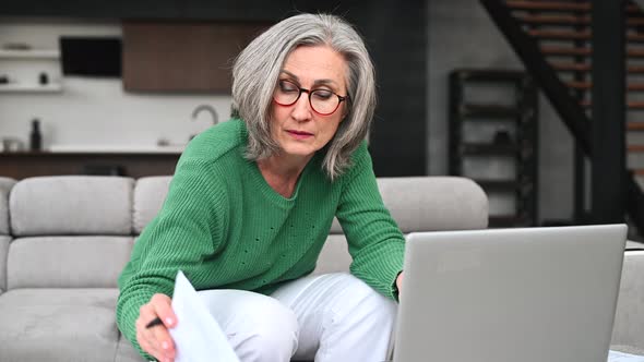 Mature Senior Woman is Using a Laptop at Home