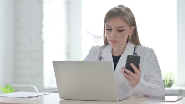 Lady Doctor Using Smartphone While Using Laptop in Clinic