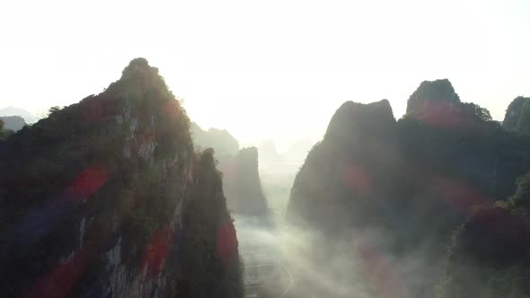 Aerial footage of beautiful sunrise over foggy karst mountain peak landscape