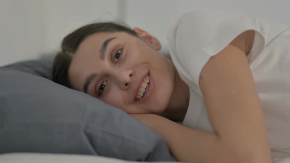 Hispanic Woman Talking on Video Call while Laying in Bed, Side Pose