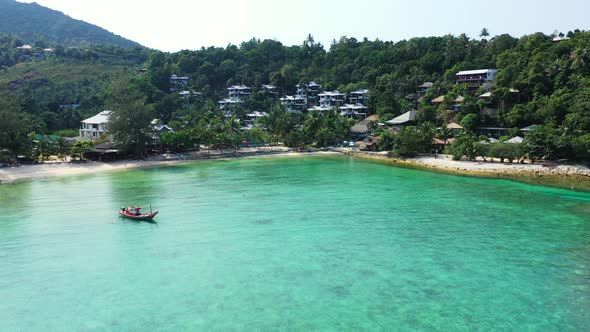 Traditional decorated fishing boat sailing slowly on calm turquoise lagoon of tropical island with s