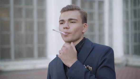 Portrait of Handsome Young Brunette Man Smoking Cigarette on Urban City Street