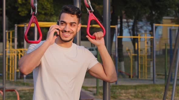 Indian Male Student in Sportswear Answers Phone During Morning Workout