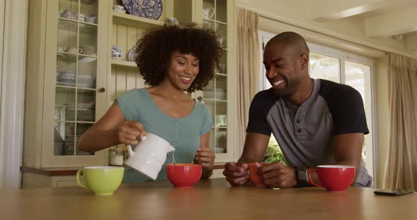 Happy mixed race couple eating breakfast in their kitchen