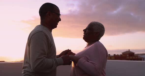 Happy mature couple dancing outdoor on patio home at sunset