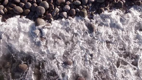 Winter Aerial Flight Top Over Waves Rolling on Artic Ocean Shore with Round Stones Ocean Waves at