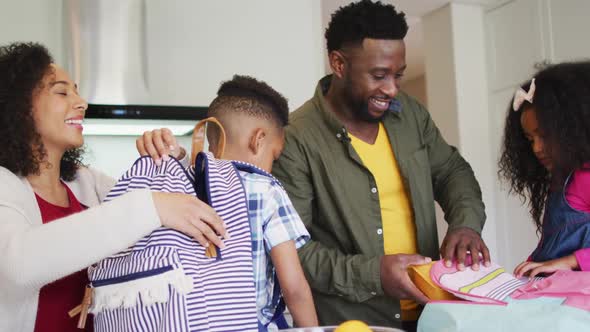 Happy african american parent preparing children for school