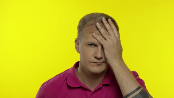 Portrait of Young Caucasian Man Posing in Pink T-shirt. Dissatisfied Guy Puts Hand on Face, Facepalm
